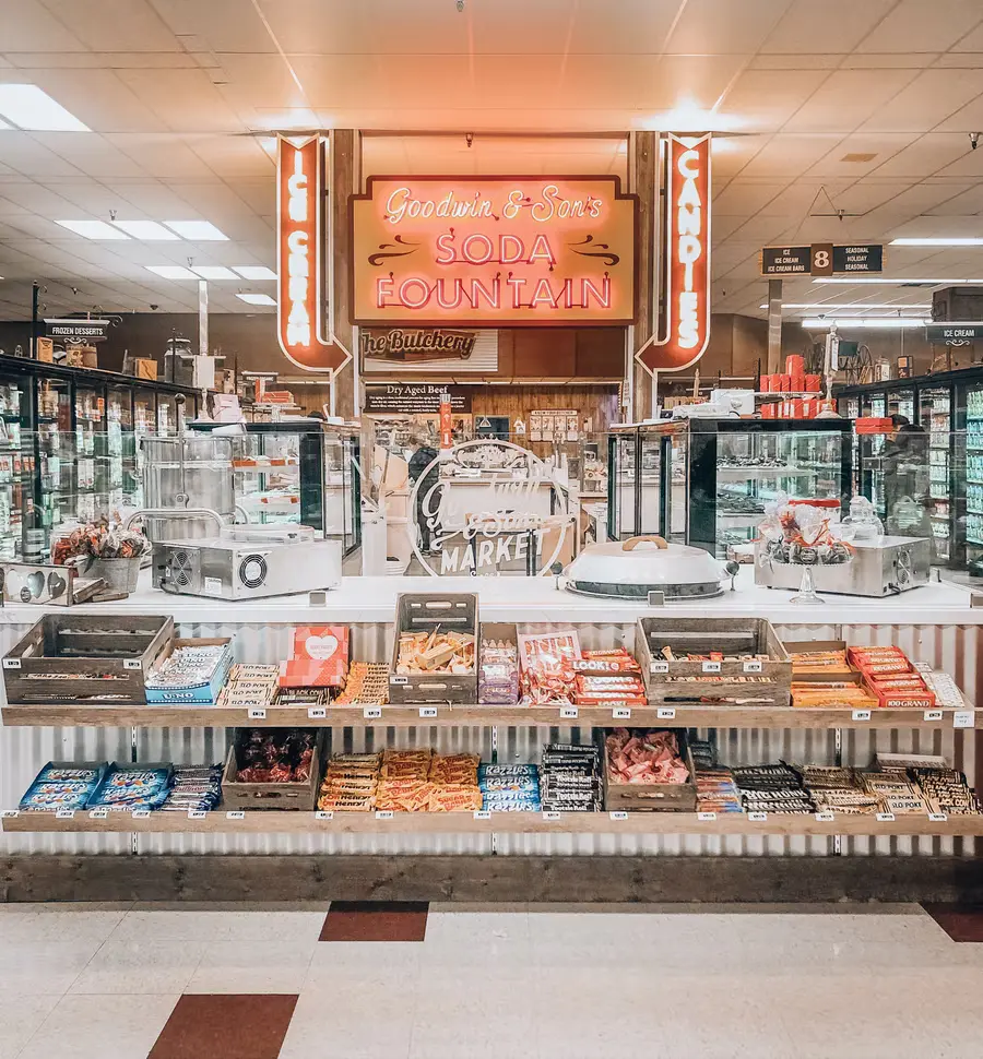 Soda shop with rows of candy on shelves and neon signs.